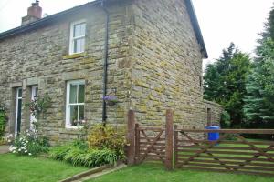 a brick house with a wooden fence in front of it at Briar Cottage in Wark