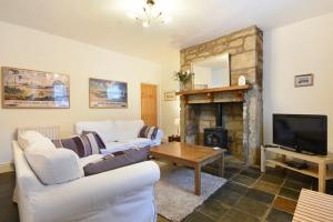 a living room with two white couches and a fireplace at Crier Cottage in Alnwick