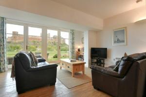 sala de estar con 2 sillas de cuero y TV en Northrawe, en Bamburgh