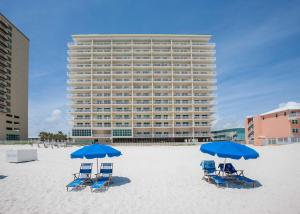 duas cadeiras azuis e guarda-sóis na praia com um edifício em Crystal Shores 204 em Gulf Shores