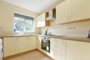 a kitchen with white cabinets and a sink and a window at Decked Out in Alnmouth