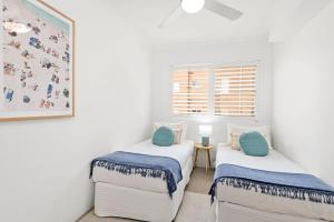 two twin beds in a room with white walls at South Pacific Unit 5 13 Shoal Bay Road in Shoal Bay