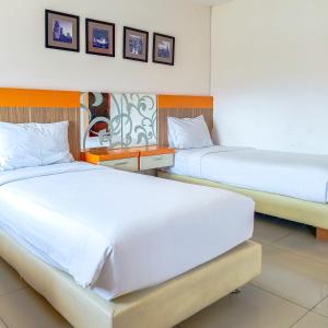 two beds in a hotel room with white sheets at High Point Serviced Apartment in Surabaya