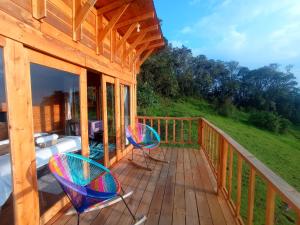 a deck with two chairs and a couch on it at Glamping Paraiso en La montaña in La Calera