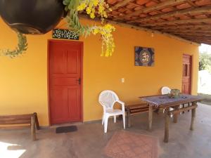 a patio with a table and chairs and a red door at Pousada Natureza in São Thomé das Letras