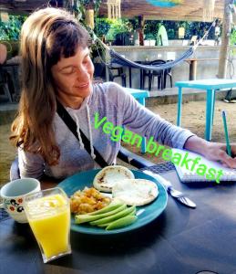 Eine Frau, die an einem Tisch mit einem Teller Essen sitzt. in der Unterkunft Freesoul Hostel in Palomino