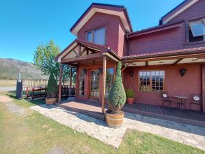 a red house with a porch with potted plants at Morrena Lodge in Torres del Paine