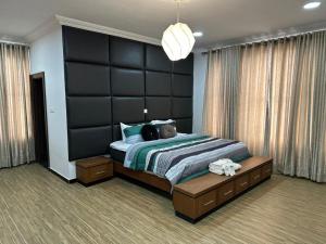 a bedroom with a large bed with a large black headboard at Nigus House Oniru in Lagos