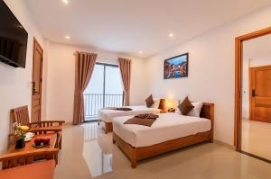 a hotel room with two beds and a television at Tomorrow Boutique Villa Hoi An in Hoi An