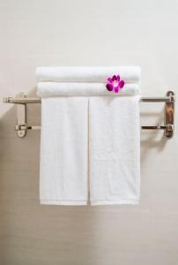 einen Handtuchhalter mit weißen Handtüchern und einer lila Blume in der Unterkunft Tomorrow Boutique Villa Hoi An in Hoi An