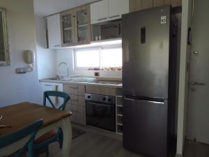 a kitchen with a stainless steel refrigerator and a table at Departamento AltoMar El Tabo Isla Negra in El Tabo