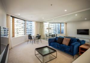 uma sala de estar com um sofá azul e uma mesa em Quay West 1301 Self- Catering em Sydney