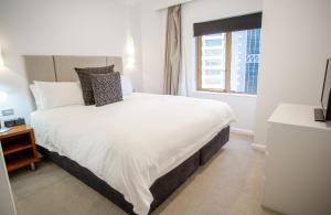 um quarto com uma grande cama branca e uma janela em Quay West 1301 Self- Catering em Sydney