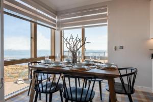 een eettafel met stoelen en een groot raam bij Keildon in Seahouses