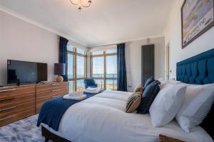 een grote slaapkamer met een groot bed en een televisie bij Keildon in Seahouses