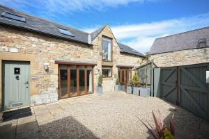 a stone house with a garage and a driveway at Links Barn in Seahouses