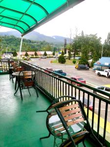 a balcony with chairs and tables and a parking lot at MJ inn in Ranau