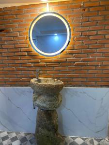 a stone sink with a mirror on a brick wall at Floor river view in Cat Tien