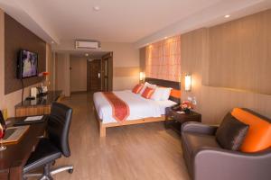 een hotelkamer met een bed en een bureau bij Dynasty Grande Hotel in Bangkok
