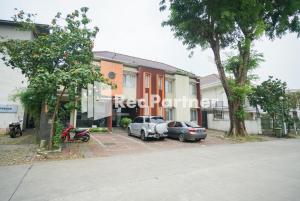 two cars parked in a parking lot in front of a building at Tirta Mansion Lippo Karawaci Mitra RedDoorz in Karawaci