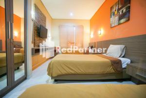 1 dormitorio con 2 camas y paredes de color naranja en Tirta Mansion Lippo Karawaci Mitra RedDoorz, en Karawaci