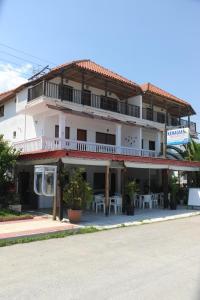 a large white building with tables in front of it at Kehagias Apartments in Nea Vrasna