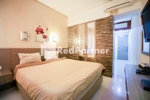 a bedroom with a large bed and a television at Tirta Mansion Lippo Karawaci Mitra RedDoorz in Karawaci