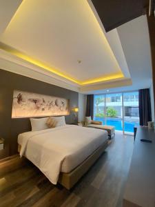 a bedroom with a large bed and a large window at Arshika Bali Sunset Road in Kuta