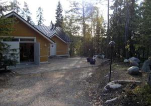 una casa amarilla con un garaje en el bosque en Villa Linnunlaulu, en Löparö
