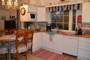 a kitchen with white cabinets and a table with a clock at Villa Linnunlaulu in Löparö