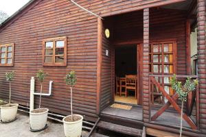 eine Holzhütte mit Topfpflanzen davor in der Unterkunft Jakaranda Cabin - Self Catering Apartment in Secunda