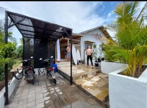 a man standing outside of a house with two motorcycles at Happy home in Huu