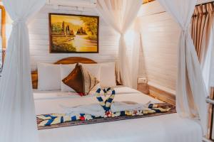 a bedroom with a bed with white curtains at Alam Nusa Bungalow Huts & Spa in Nusa Lembongan