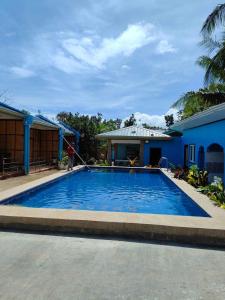 une personne arrose une grande piscine bleue dans l'établissement R&D Traveller's Inn, à Anda