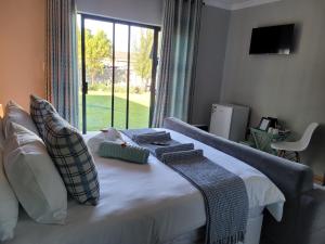 ein Schlafzimmer mit einem Bett mit Kissen und einem Fenster in der Unterkunft Ayana bnb in Bloemfontein