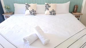 Una cama con sábanas blancas y dos toallas. en The Carmel Yamba en Yamba