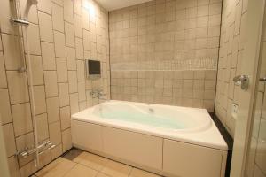 a white bath tub in a bathroom with tiles at Hotel THE ATTA Adult Only in Tokyo
