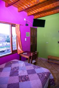 1 dormitorio con paredes moradas y verdes y 1 cama en El Shaddai en Tilcara