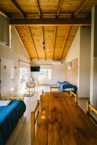 Zimmer mit einem Holztisch und blauen Betten in der Unterkunft Balcón del Cerro in Sierra de la Ventana