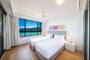 a bedroom with a bed and a large window at Pinnacles in Airlie Beach