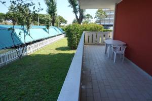 een patio met een tafel en stoelen aan de zijkant van een gebouw bij Homely apartment for up to 6 guests with pool in Porto Santa Margherita di Caorle