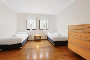 2 camas en una habitación con 2 ventanas en Lake Tyers Beach House, en Lake Tyers