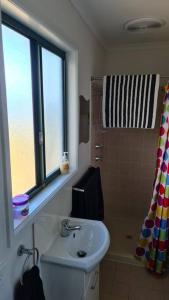 baño con lavabo, ventana y ducha en Coorong Lakeside Cottage, en Meningie