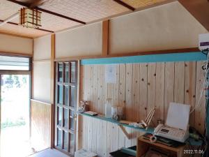 Suo Oshima的住宿－イマジンウエストオーシャン（ImagineWestOcean），一间设有木墙的客房,并在书桌上配有一台笔记本电脑