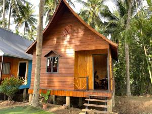 a small wooden house with a porch in front of trees at Bungalow - Homestay LÀNG BÈ in Ben Tre