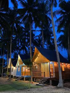 a wooden house with palm trees in the night at Bungalow - Homestay LÀNG BÈ in Ben Tre