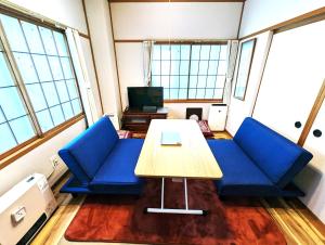 a room with blue couches and a wooden table at 和宿 湯沢チャオ in Yuzawa