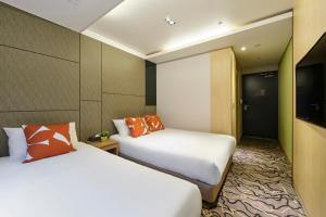 pokój hotelowy z 2 łóżkami i telewizorem w obiekcie JEJU Western Grace Hotel w mieście Seogwipo