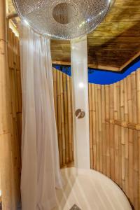 La salle de bains est pourvue d'une douche avec un rideau blanc. dans l'établissement Cliffside Bamboo Treehouse with Pool and View, à Bungbungan