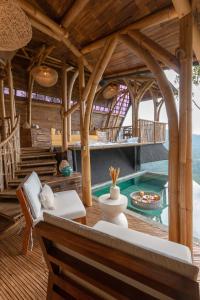 Bungbungan的住宿－Cliffside Bamboo Treehouse with Pool and View，室外客厅设有游泳池和木制天花板